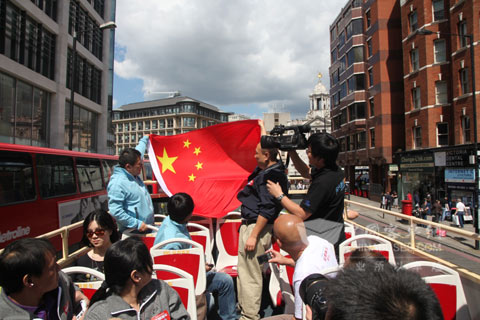中国游客们在安凯双层车上扬起国旗为奥运健儿助威